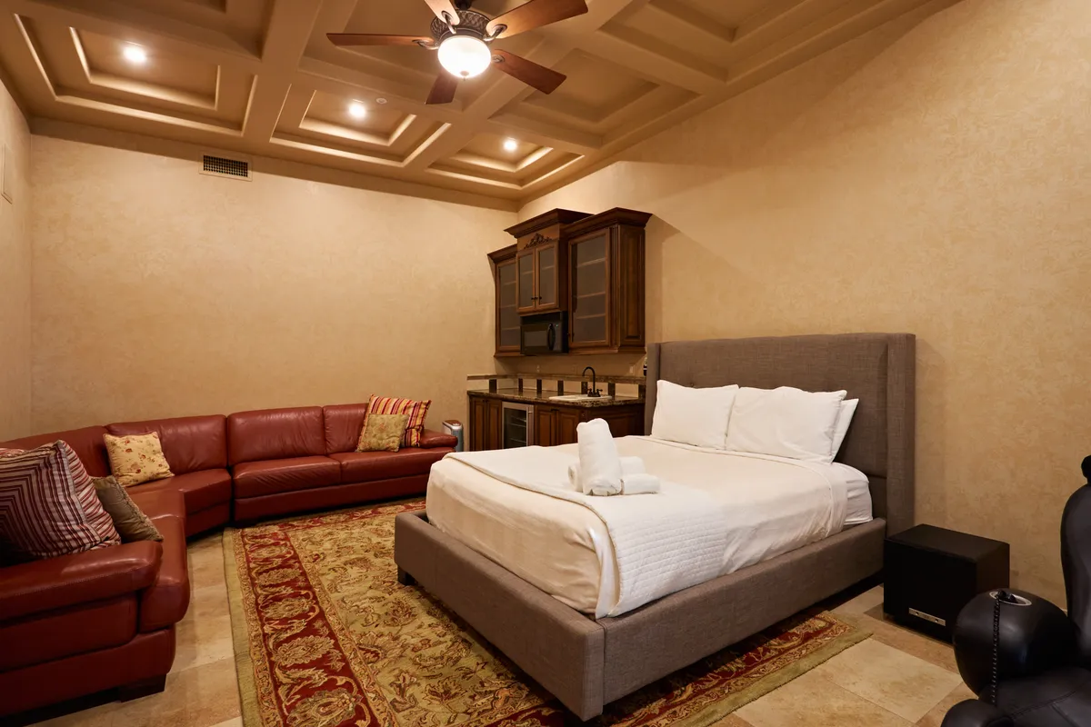 This image displays a cozy casita interior with a comfortable bed, a sofa, a decorative rug, and a compact kitchenette. The arrangement feels private and homey, perfect for guests seeking their own retreat within the estate.