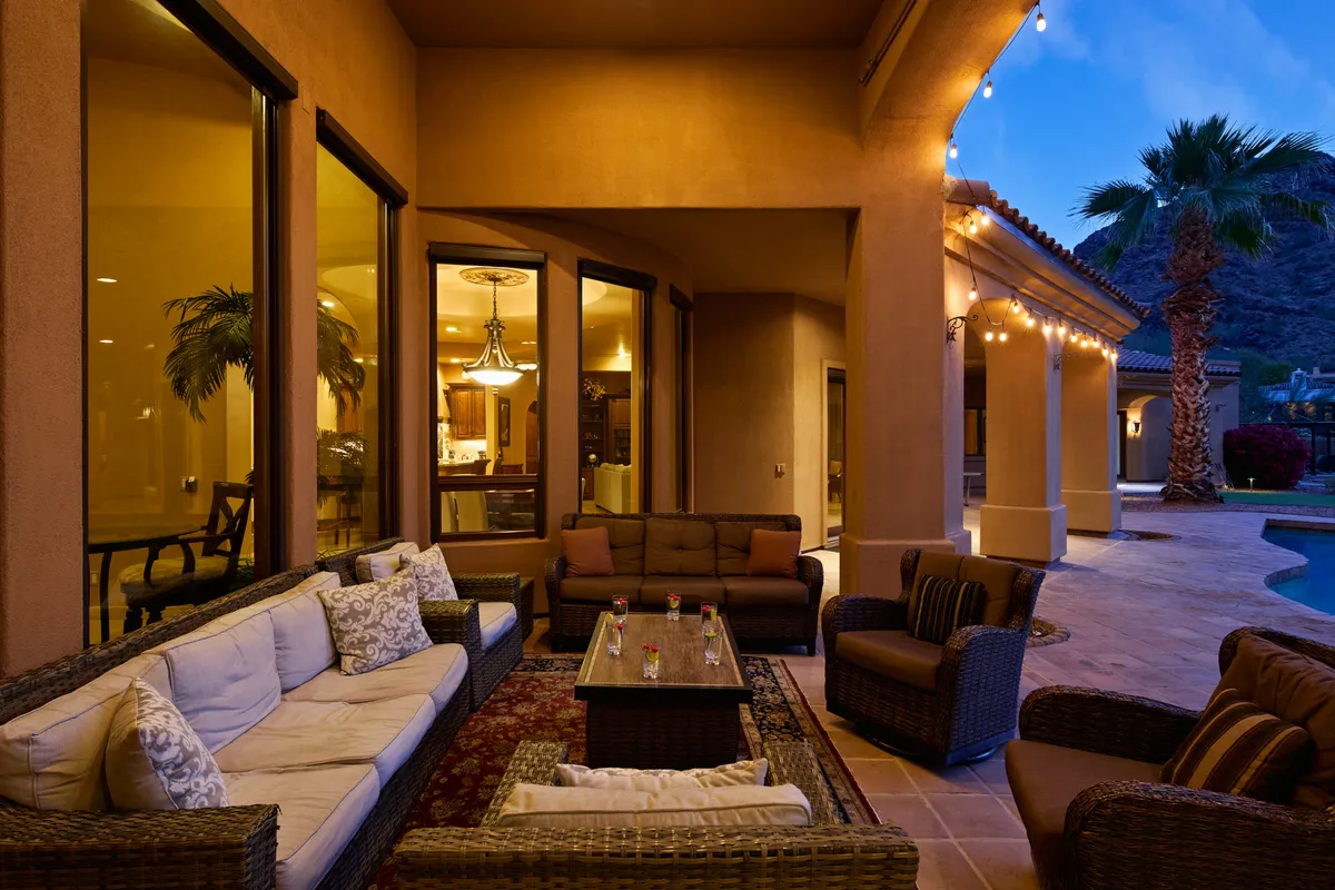 An exterior view featuring a stylish outdoor seating area with a decorative table and soft outdoor lighting. The cozy arrangement invites conversation and informal gatherings against a backdrop that suggests both comfort and intimacy.